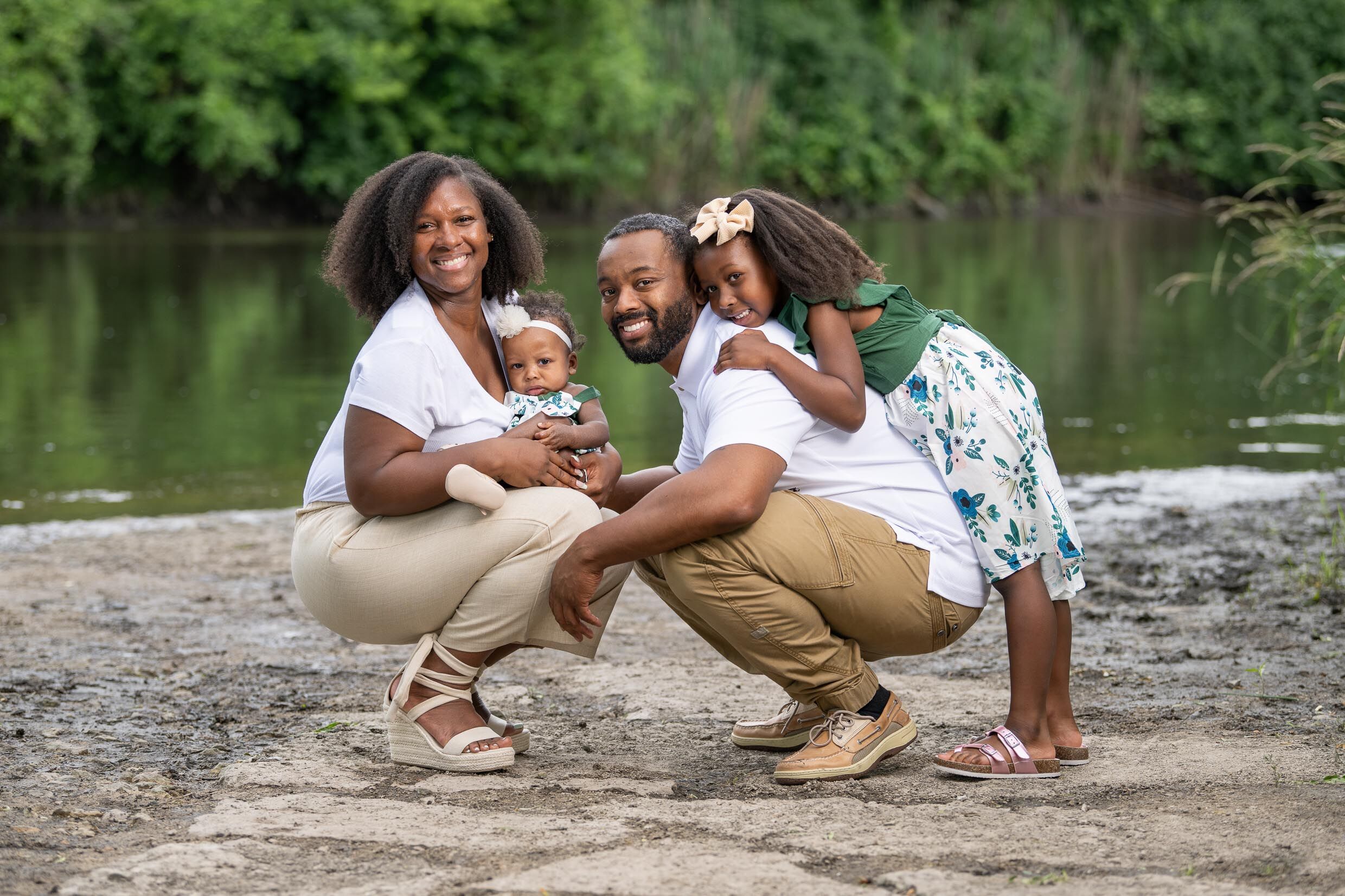 African American family of four seated in front of river during the summer in Chicago.